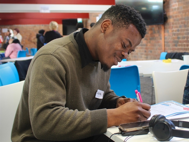 A man sat at a desk writing on paper