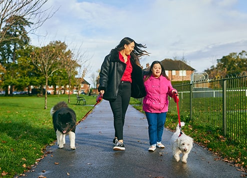 A person supporting another person taking a dog for a walk